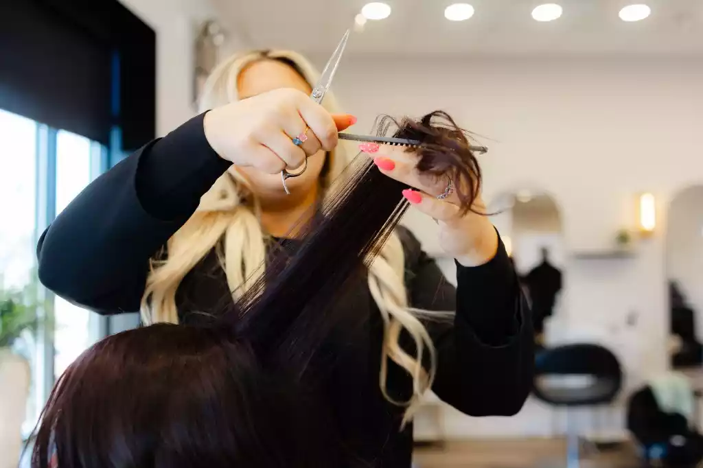 A stylist precision-cutting a client's hair with shears and comb